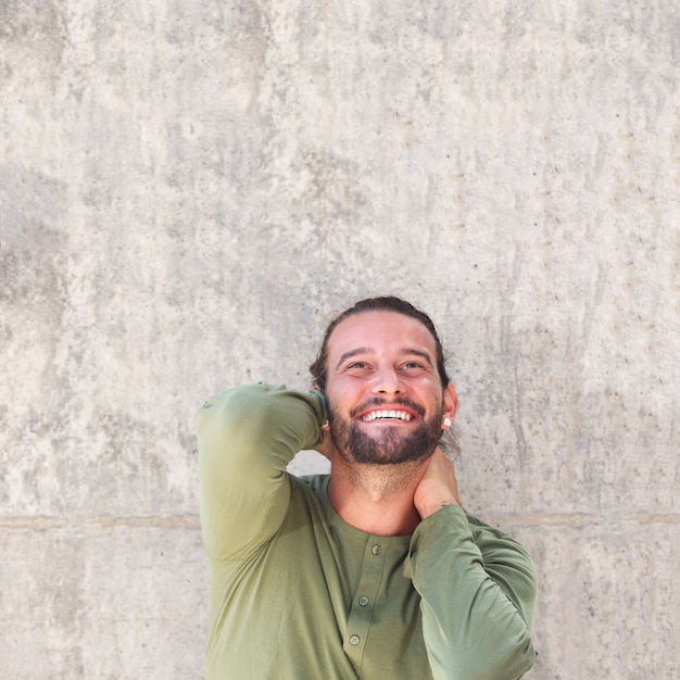 Uomo felice che sorride e che si leva in piedi con le mani dietro la testa