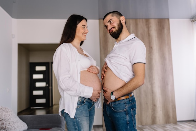 Uomo felice che tocca la pancia della donna incinta sorridente sdraiata sul divano