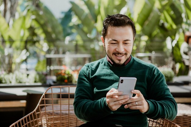 Uomo felice che usa uno smartphone in un bar