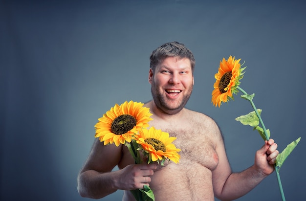 Uomo felice con bouquet di girasoli, isolato su gray