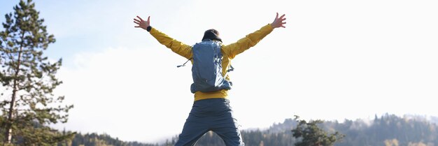 Uomo felice con le braccia aperte che salta il lago e le montagne sullo sfondo escursionista con zaino