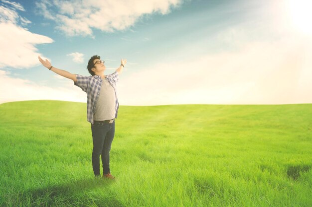 Uomo felice con le braccia spalancate godendosi la primavera sul prato verde Concetto di estate o primavera