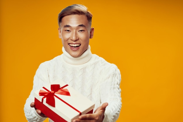 Uomo felice con un regalo in una scatola su uno sfondo giallo sorridente