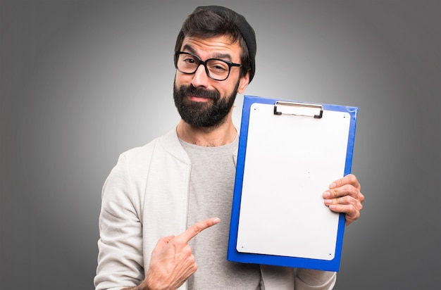 Uomo felice dei pantaloni a vita bassa con la cartella su fondo grigio