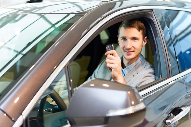 Uomo felice dentro la nuova automobile