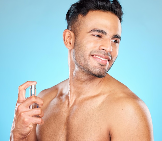 Uomo felice e profumo per aroma di fragranza e profumo virile su sfondo blu studio Giovane maschio sano gentiluomo latino e acqua di colonia per la bellezza naturale fresca e buon odore per l'igiene e il relax