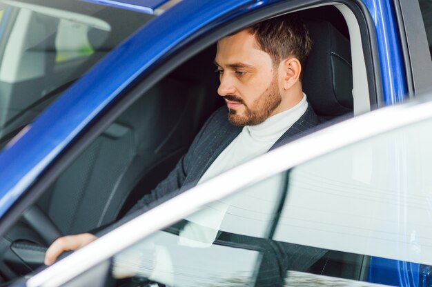 Uomo felice elegante attraente in buona macchina