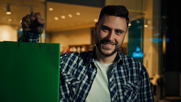 Uomo felice in piedi in un centro commerciale vestiti alla moda in vendita in un negozio di boutique con borse regalo