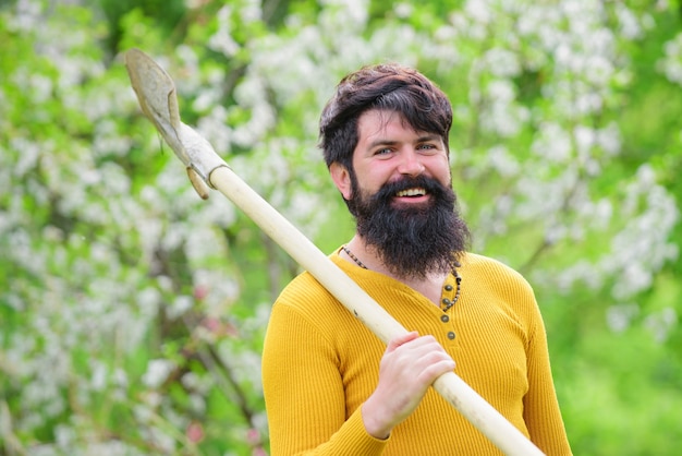 Uomo felice nel giardino di primavera. Giardiniere in fattoria Eco con attrezzi da giardinaggio che piantano con la pala.