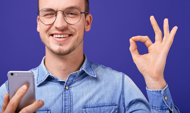 Uomo felice sorridente nell'occhiolino blu della camicia del denim