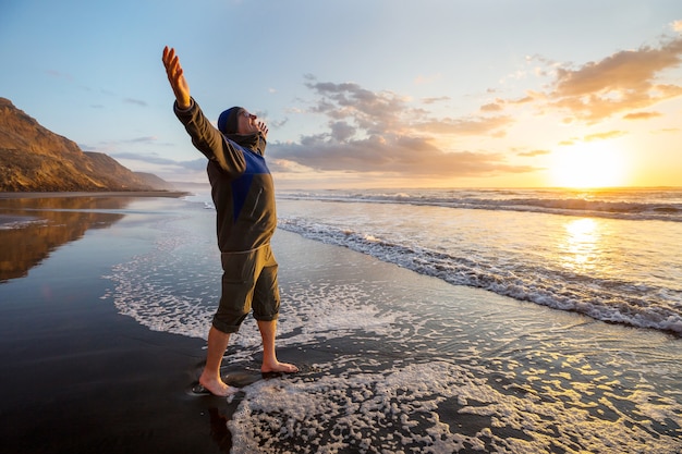 Uomo felice sull'alba in spiaggia. Concetto di viaggio ed emozione