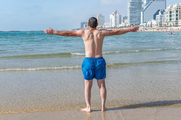 Uomo felice sulla bellissima spiaggia in libertà a braccia aperte