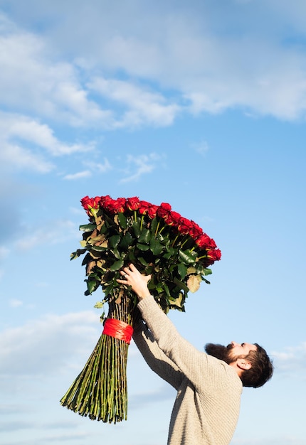 Uomo fidanzato con bouquet di rose. Concetto di regali di San Valentino. Bel ragazzo che dà fiori alla ragazza.