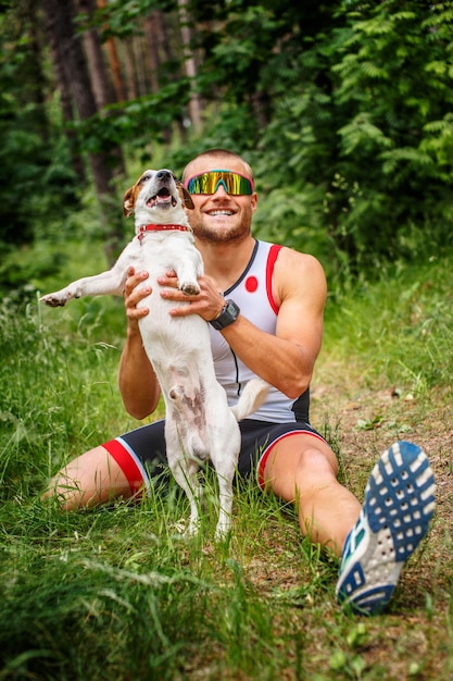 Uomo fitness in abbigliamento sportivo con il suo cane nella foresta.