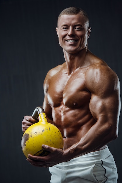 Uomo fitness pompando i muscoli con kettlebell