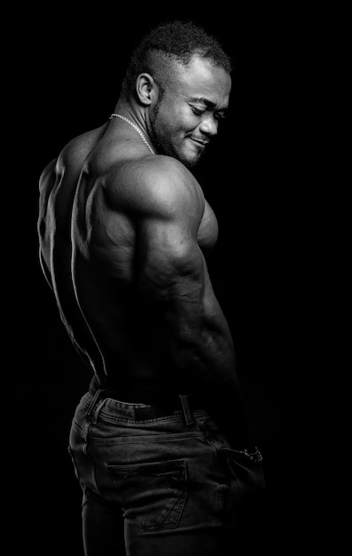 Uomo forte artistico chiave bassa su sfondo nero. Ritratto in bianco e nero di metà rivolto all'atleta della fotocamera.