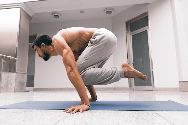 Uomo forte atletico che pratica posa yoga difficile.