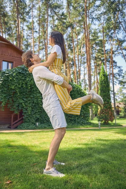 uomo forte che tiene bella donna sulle mani all'aperto