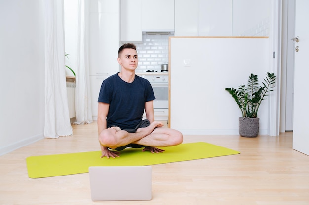 Uomo forte e sicuro di sé che solleva il corpo con le mani che praticano yoga nella cucina di casa