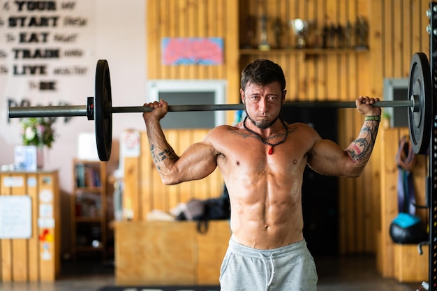 Uomo forte in una palestra che fa affondi ponderati