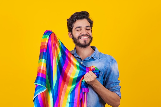 Uomo gay felice che si diverte a tenere la bandiera arcobaleno simbolo della comunità LGBTQ
