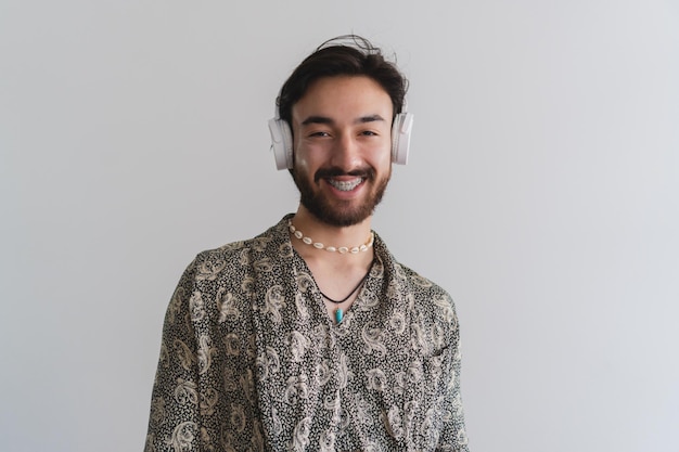 Uomo gay latino queer che guarda l'obbiettivo con un sorriso mentre indossa un auricolare wireless