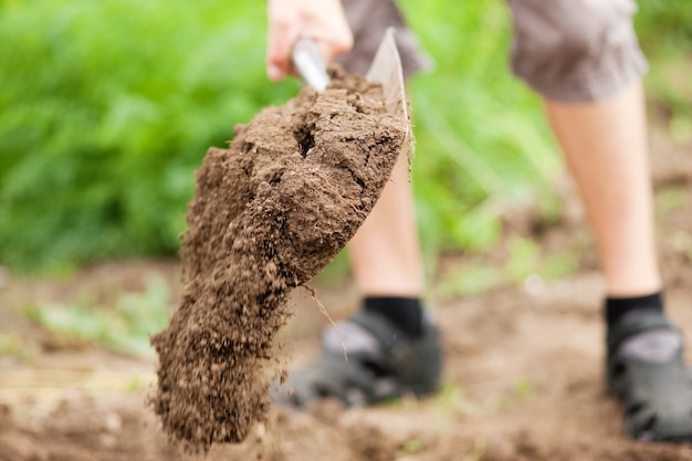 Uomo giardiniere - solo piedi da vedere - scavare il terreno in primavera con una vanga per preparare il giardino