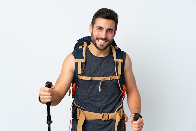 Uomo giovane alpinista con un grande zaino e bastoncini da trekking isolato sulla risata bianca della parete