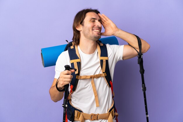 Uomo giovane alpinista con un grande zaino sopra la parete isolata che sorride molto