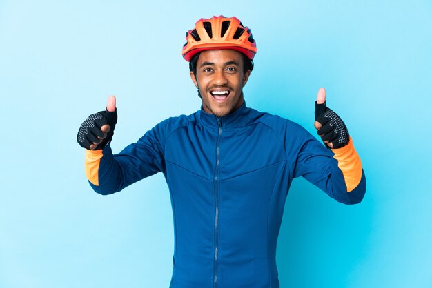 Uomo giovane ciclista con trecce su sfondo isolato dando un pollice in alto gesto