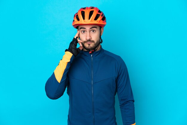 Uomo giovane ciclista isolato su sfondo blu pensando un'idea