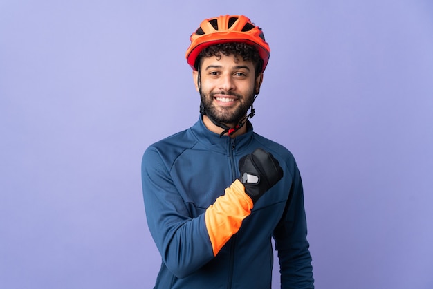 Uomo giovane ciclista marocchino isolato su viola che celebra una vittoria