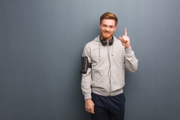 Uomo giovane di redhead di forma fisica che mostra numero uno