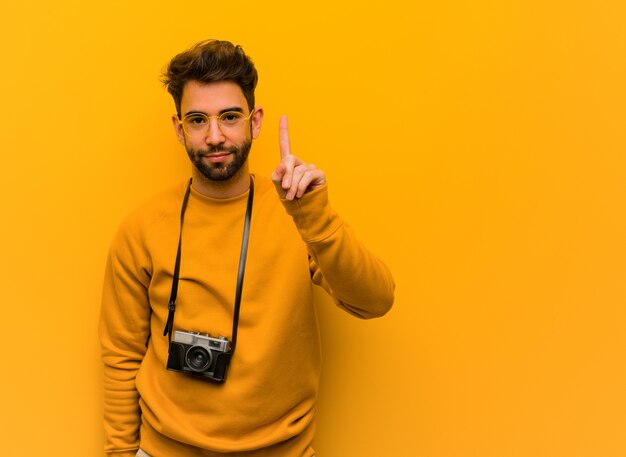 Uomo giovane fotografo che mostra il numero uno