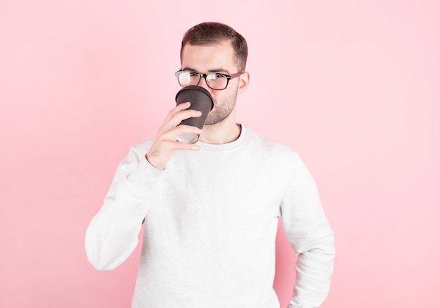 Uomo giovane hipster che beve caffè sopra la parete colorata