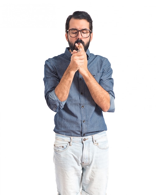 Uomo giovane hipster che fuma sopra priorità bassa bianca