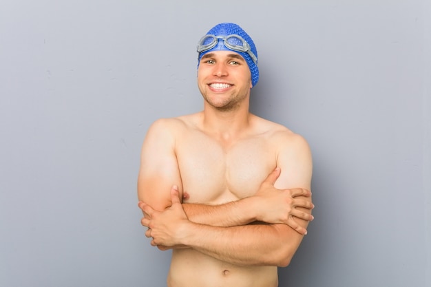 Uomo giovane nuotatore professionista che si sente sicuro, incrociando le braccia con determinazione.
