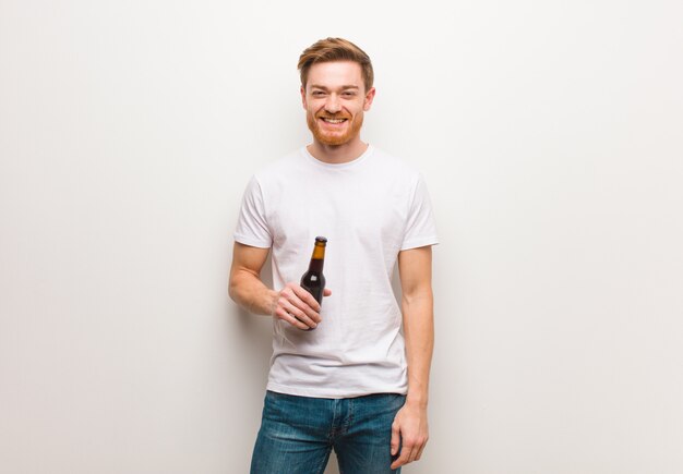 Uomo giovane rossa allegro con un grande sorriso. Tenendo una birra.