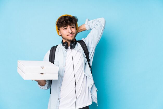 Uomo giovane studente arabo che tiene pizze isolate toccando la parte posteriore della testa, pensando e facendo una scelta.