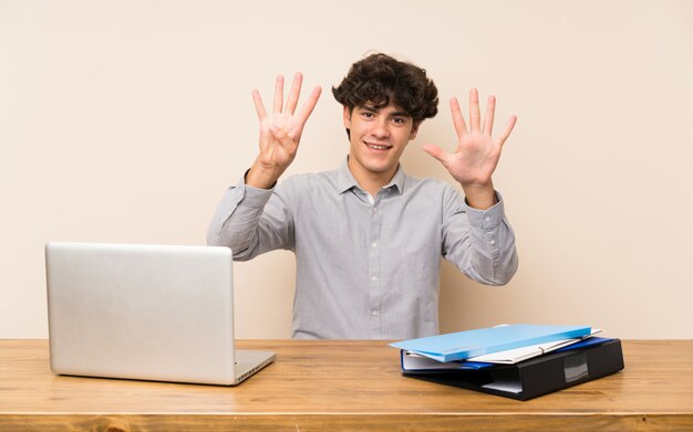 Uomo giovane studente con un computer portatile che conta nove con le dita