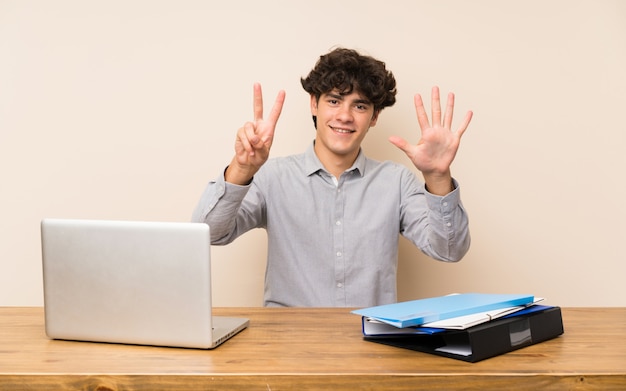 Uomo giovane studente con un computer portatile che conta sette con le dita