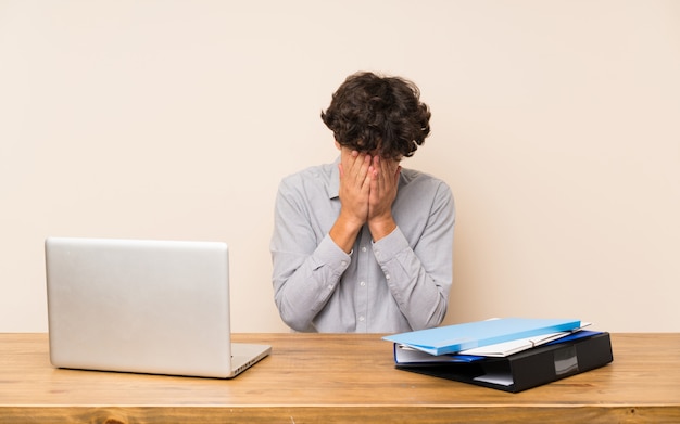 Uomo giovane studente con un computer portatile con espressione stanca e malata