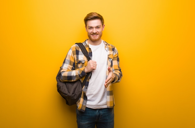 Uomo giovane studente di redhead raggiungendo per salutare qualcuno