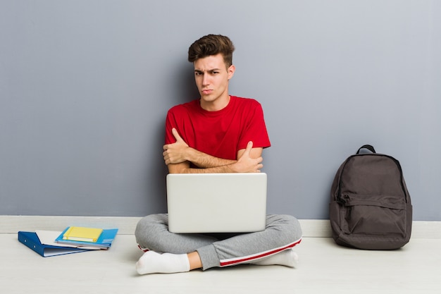 Uomo giovane studente seduto sul suo pavimento di casa in possesso di un computer portatile