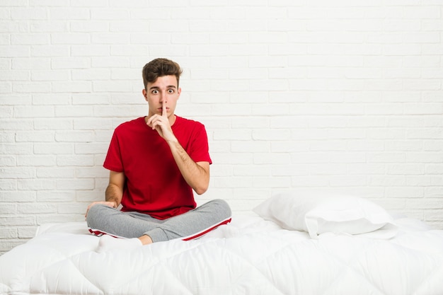 Uomo giovane studente studente sul letto mantenendo un segreto o chiedendo silenzio.