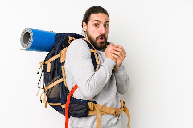 Uomo giovane viaggiatore con zaino e sacco a pelo isolato su un bianco spaventato e impaurito.