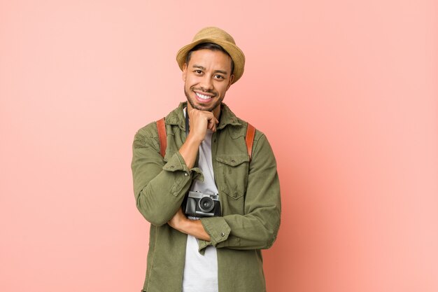 Uomo giovane viaggiatore filippino sorridente felice e fiducioso, toccando il mento con la mano.