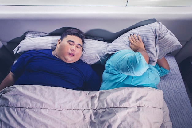 Uomo grasso che russa mentre dorme accanto a sua moglie