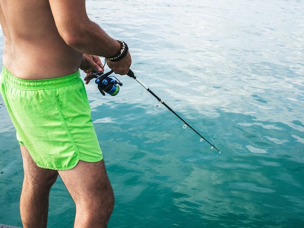 Uomo grasso della pancia che pesca nel mare