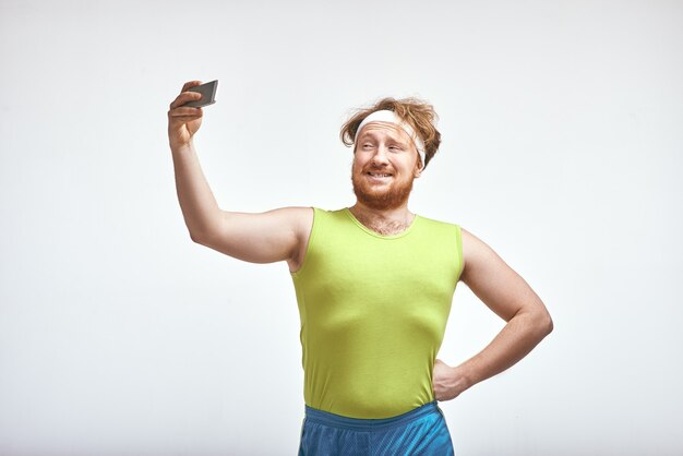 Uomo grassoccio barbuto dai capelli rossi che sorride e si fa un selfie